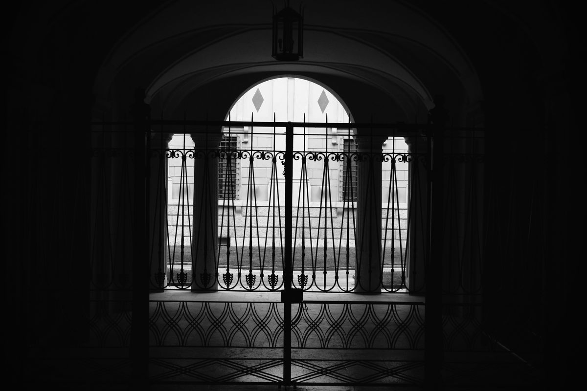 Schmiedeeisernes Hoftor als Silhouette in einem Torbogen