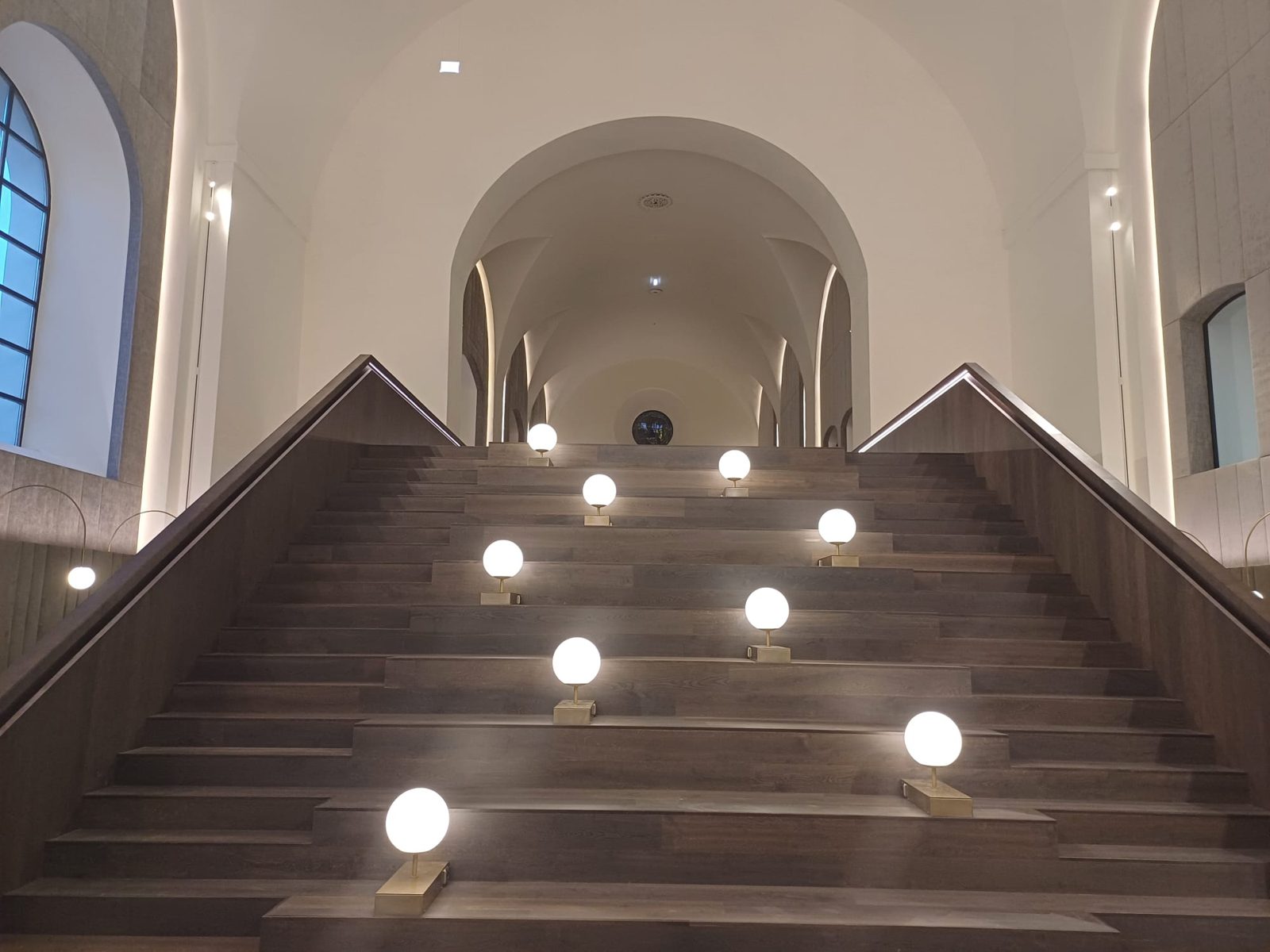 Kugelleuchten auf den Stufen einer großen Holztreppe in einem Gewölbebau
